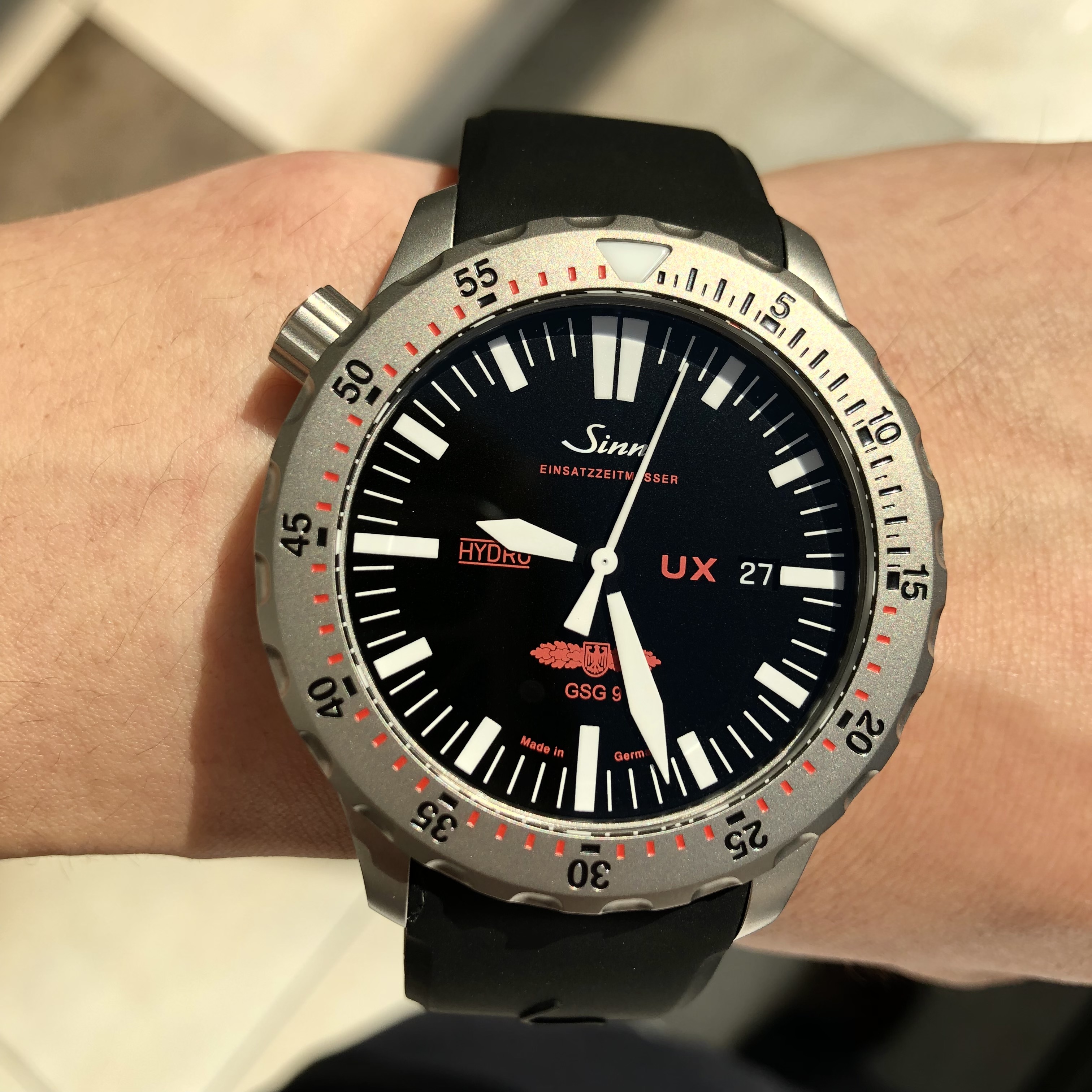 [Sinn (ジン)正規取り扱い商品]<br />
<br />
UX<br />
<br />
Ref.UX.GSG9<br />
<br />
¥418,000 (税込)<br />
<br />
ジンには、多くの名作、<br />
<br />
例えば<br />
<br />
パイロットウォッチの103、<br />
<br />
ダイバーズウォッチの603.EZM3<br />
<br />
などなど数え上げるとキリがありませんが、<br />
<br />
本当に実用時計としての名作がたくさんあります。<br />
<br />
ジンファンの方は、その名作で自分の好きなものを<br />
<br />
コンプリートしていきたい！<br />
<br />
と思って頂いている方が多くいらっしゃいます！！<br />
<br />
そのようなジンファンの方で、<br />
<br />
多くの方がコンプリートの候補にあげていらっしゃるのが、<br />
<br />
このUX.GSG9です！<br />
<br />
ドイツの対テロリズム特殊部隊GSG9の要請により開発されたこちらのモデル。<br />
<br />
製品のほとんどが機械式時計のモデルのジンのラインナップの中で、<br />
<br />
珍しいクオーツモデルです。<br />
<br />
それにも理由があり、<br />
<br />
特殊なオイルを時計ケースに封入することで<br />
<br />
5,000mという高い防水性を実現させています。<br />
<br />
また、オイルが封入されていることにより、<br />
<br />
空気の屈折率をなくし、<br />
<br />
角度が付いた状態で時計を見ても、<br />
<br />
しっかりと時間が確認できるようになっています。<br />
<br />
それに加え、<br />
<br />
このモデルではリューズを通常と逆の左側に付けています。<br />
<br />
重火器が引っかからないよう安全性を重視した配慮がされており、<br />
<br />
常に危険と接する特殊部隊にとって事故につながる要素を<br />
<br />
事前に排除することに役立っています。<br />
<br />
こんなに素敵なプロスペックのモデル。<br />
<br />
ぜひ店頭でご覧ください！