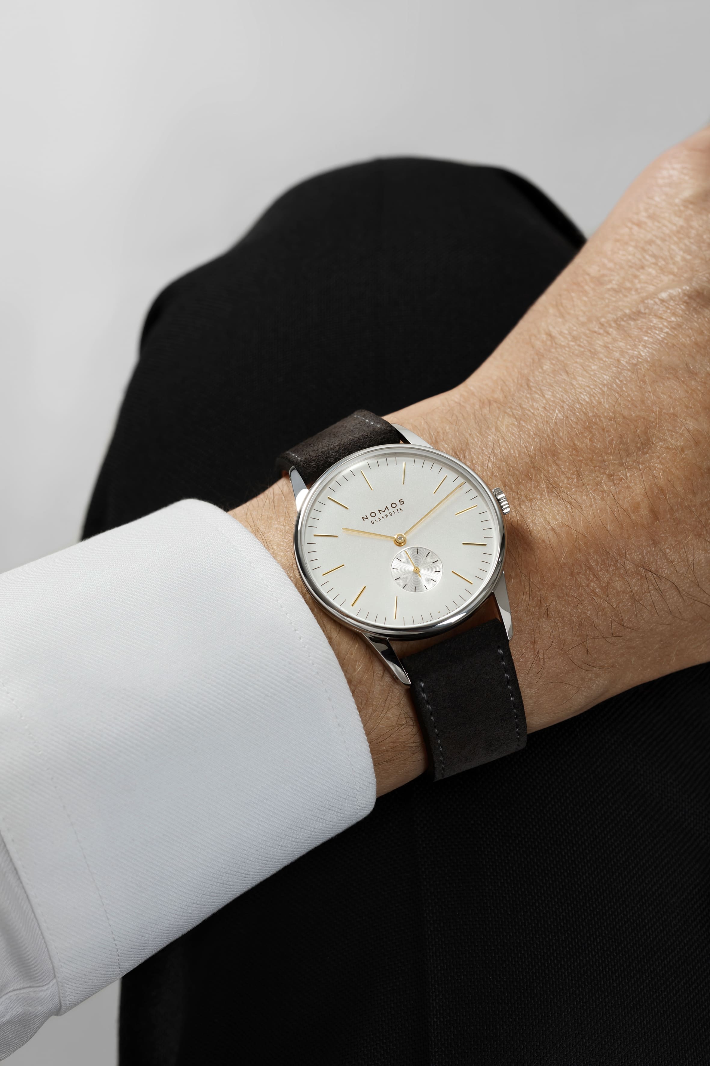 《クラシックなスーツにもカジュアルなスタイルにもマッチするNOMOS ORION 38 Silver（品番 OR1A3GS238 / 379）は、ドーム型サファイアガラスと繊細なアンスラサイトのベロアストラップが手首を美しく演出。洗練されたゴールド針とインデックスが大人の気品を引き立て、控えめながら圧倒的な存在感を放ちます。ユニセックスで楽しめるためペアウォッチとしても最適。ノモスらしいデザイン哲学が詰まった一本。》